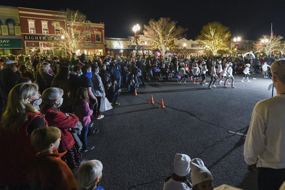 A crowd watches a performance Friday, Dec. 11, 2020, during Christmas in a Railroad Town festivities in downtown Opelika, Ala. Doctors and nurses caring for the sickest COVID-19 patients are doing what they can to get through the holidays while neighbors and friends indulge in Christmas parades and tree lightings. (AP Photo/Julie Bennett)