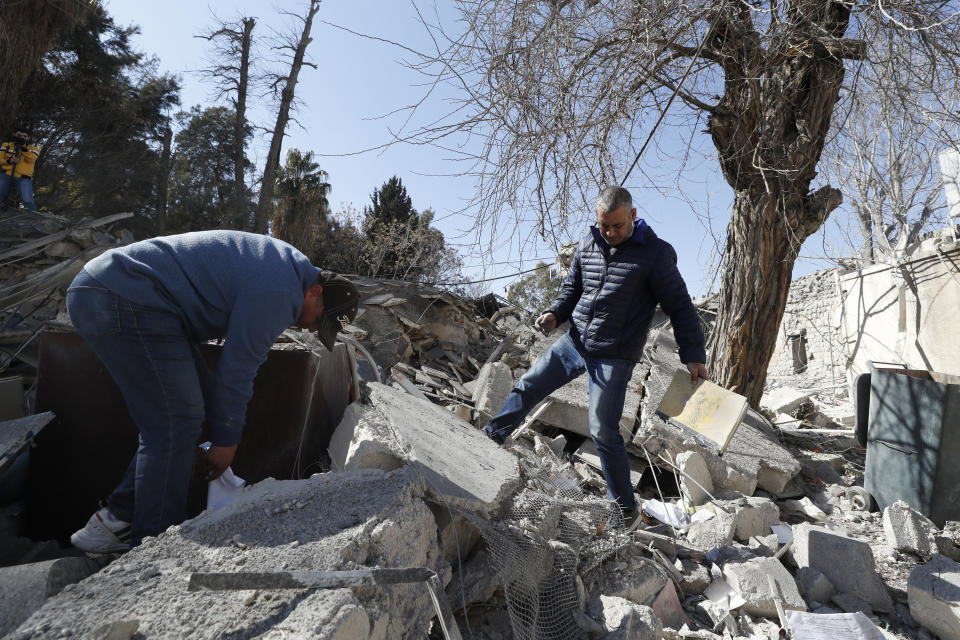 People inspect the damage of a medieval citadel after an early morning Israeli airstrike in the capital city of Damascus, Syria, Sunday, Feb. 19, 2023. Syrian state news reported that Israeli airstrikes have targeted a residential neighborhood in central Damascus. (AP Photo/Omar Sanadiki)