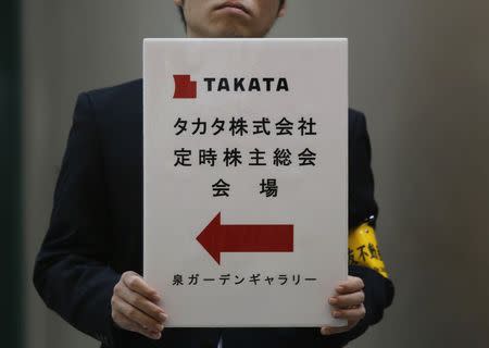 An employee of Japanese auto parts maker Takata Corp holds a sign board of the company's Annual General Meeting at an exit of a station near the venue in Tokyo in this June 26, 2014 file photo. REUTERS/Yuya Shino/Files
