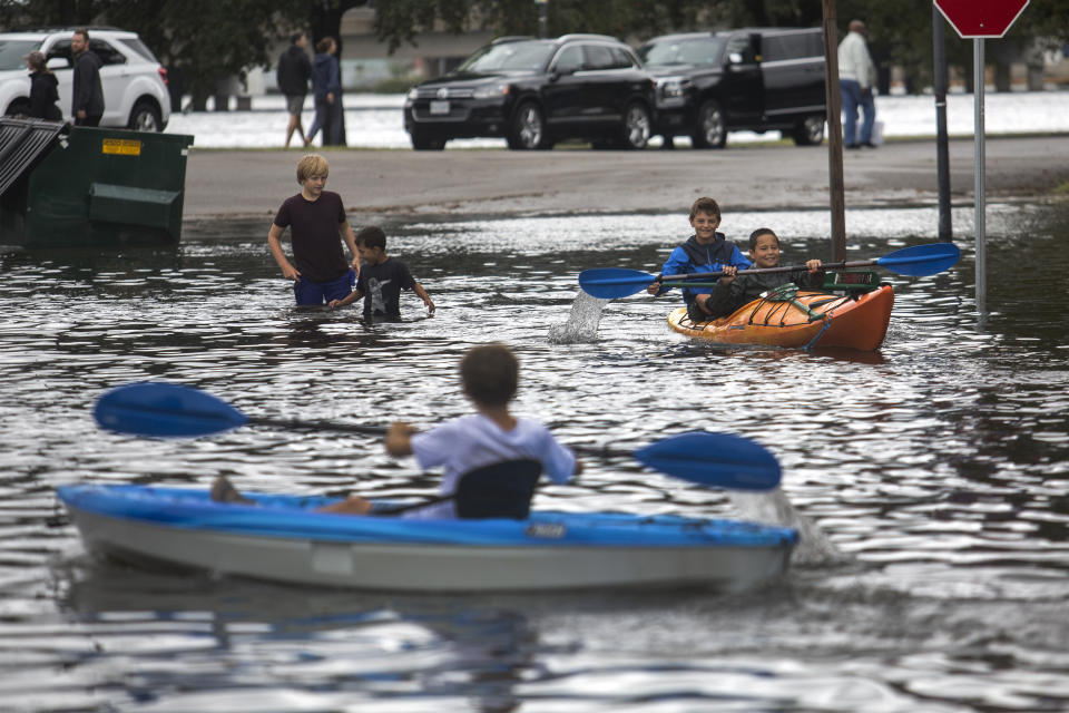 Kids kayak through the flooded streets near the corner of Mowbray Arch and Botetourt Street after the storms caused by Hurricane Dorian on Friday, Sept. 6, 2019, in Norfolk, Va. (Sarah Holm/The Virginian-Pilot via AP)