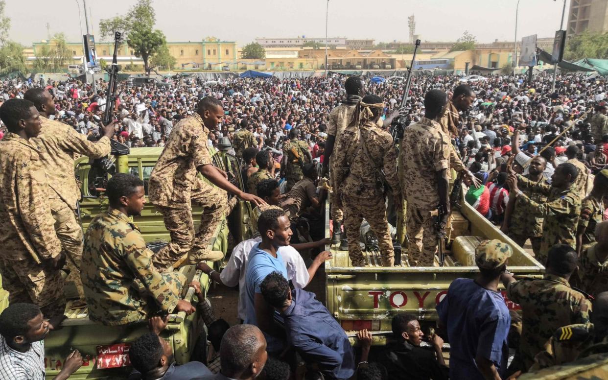 Sudanese soldeirs stand guard on armoured military vehicles as demonstrators continue their protest - AFP