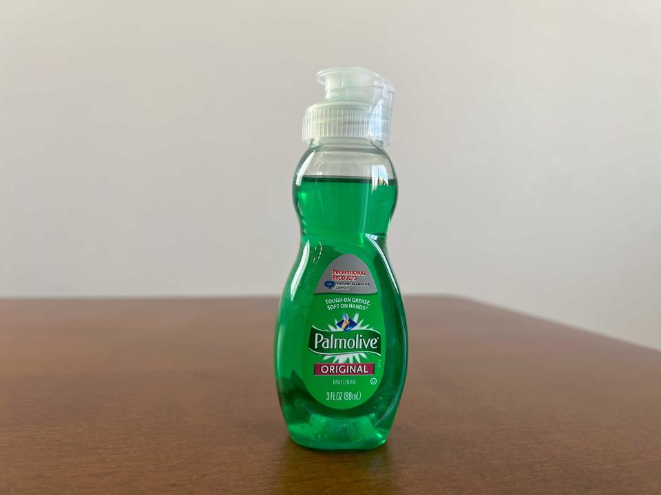 A picture of green dishwasher liquid soap in a small bottle on a table.