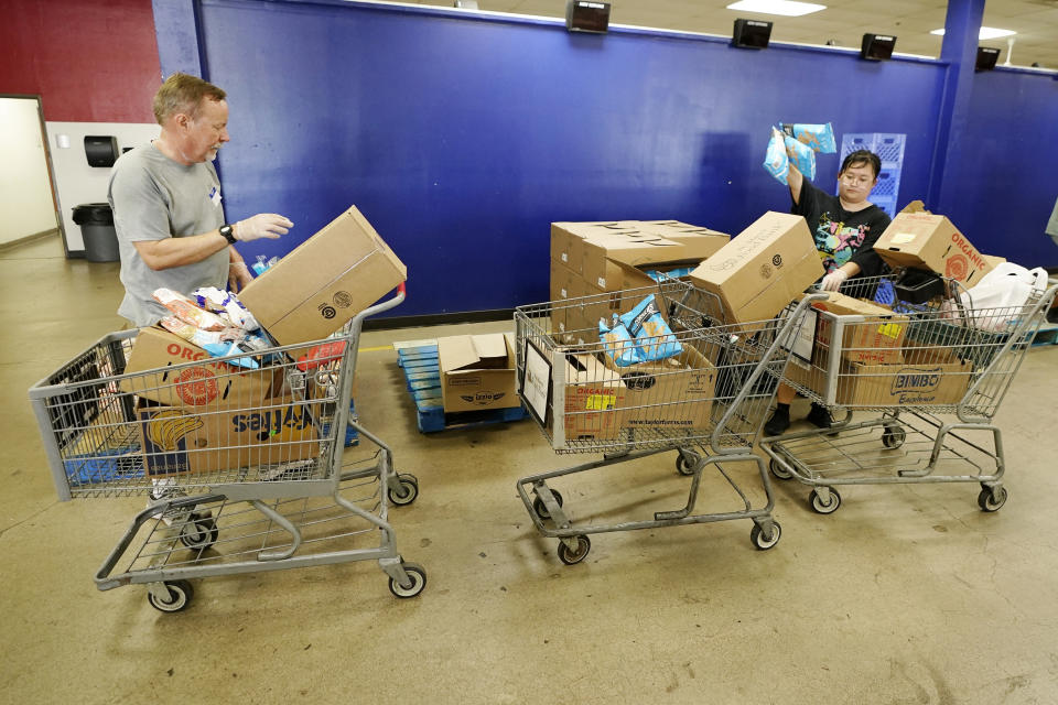 Volunteers fill up grocery carts with food boxes for distribution into drive through vehicles at the St. Mary's Food Bank Wednesday, June 29, 2022, in Phoenix. Long lines are back at food banks around the U.S. as working Americans overwhelmed by inflation turn to handouts to help feed their families. (AP Photo/Ross D. Franklin)