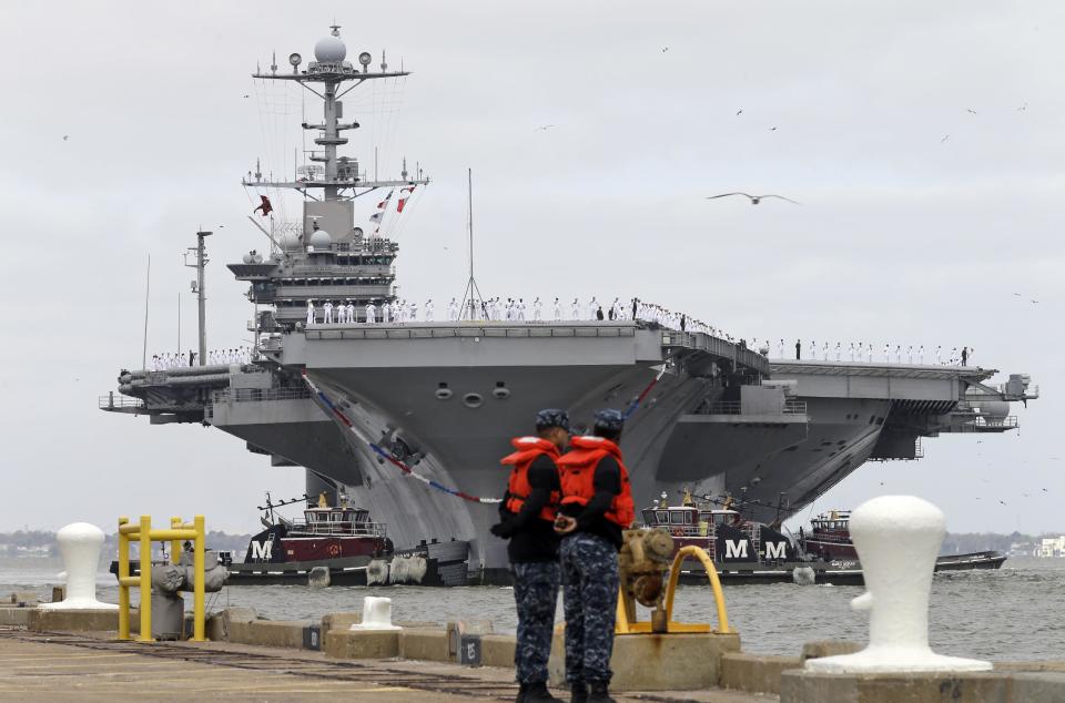 Dockworkers watch as the nuclear aircraft carrier Harry S. Truman approaches the pier at Naval Station Norfolk in Norfolk, Va., Friday, April 18, 2014. The Carrier Strike Group is returning form a 9-month deployment to the Middle East. (AP Photo/Steve Helber)