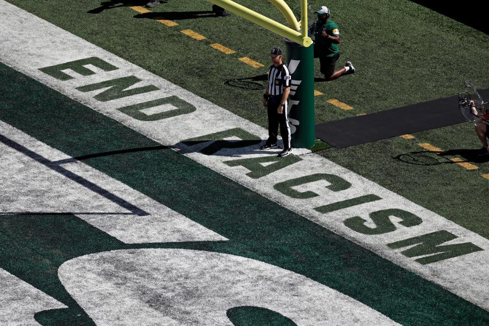 Back judge Rich Martinez stands in the end zone next to the social justice message "End Racism during the Patriots-Jets game on Sept. 19, 2021, in East Rutherford, N.J.