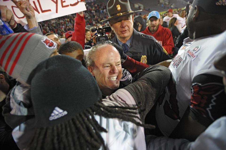 Arkansas State interim head coach John Thompson, center, is surrounded by players and fans as they celebrate their team's victory over Ball State 23-20 in the GoDaddy Bowl NCAA college football game in Mobile, Ala., Sunday, Jan. 5, 2014. (AP Photo/G.M. Andrews)