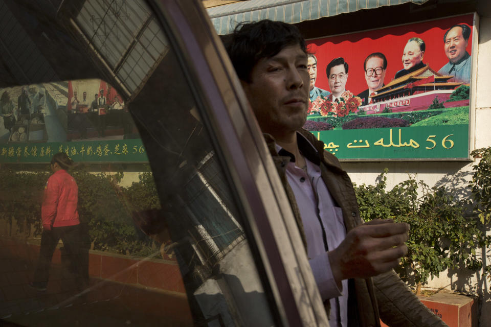 In this Monday, March 3, 2014 photo, a Uighur man walks past a propaganda poster, partially in Uighur language, urging for ethnic unity in a community shared by both ethnic Uighur and Han Chinese residents in Kunming, in western China's Yunnan province. China said the vicious slashing spree Saturday that killed 29 people in the southern city was the work of separatists linked to international terrorism, but the assailants’ homespun methods and low-tech weapons - nothing more than long knives - have led some analysts to suspect they didn’t get outside help. (AP Photo/Alexander F. Yuan)