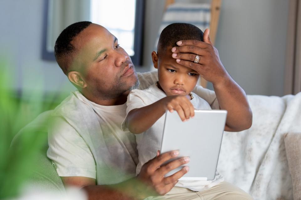 An adult and child use a tablet to see a doctor as part of a telehealth visit.