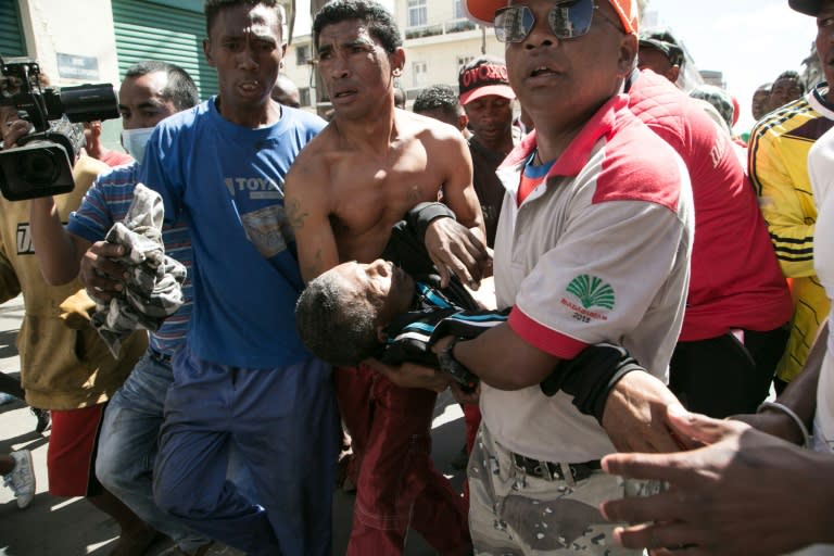 People carry a man shot in the abdomen during clashes with police at an opposition protest against new election laws in Madagascar