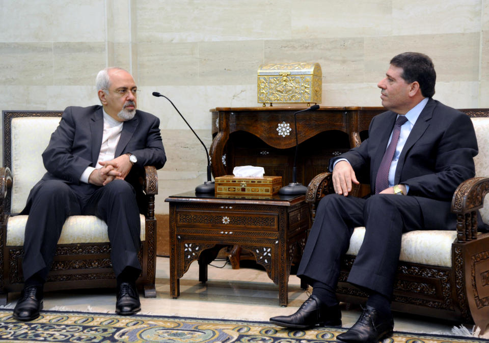 In this photo released by the Syrian official news agency SANA, Iranian Foreign Minister Mohammad Javad Zarif, left, meets with Syrian Prime Minister Wael al-Halqi, right, in Damascus, Syria, Wednesday, Jan. 15, 2014. Syrian President Bashar Assad and Zarif have held talks about next week's United Nations conference in Montreux, Switzerland, aimed at trying to resolve the three-year deadly conflict. (AP Photo/SANA)