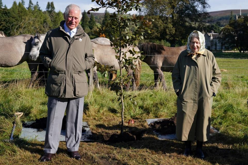 Queen Elizabeth II and Britain's Prince Charles, Prince of Wales pose alongside the tree which they planted to mark the start of the official planting season for the Queen's Green Canopy (QGC) at the Balmoral Cricket Pavilion, Balmoral Estate in Scotland in October (POOL/AFP via Getty Images)