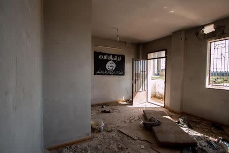 An Islamic State flag hangs on the wall of an abandoned building in Tel Hamis in Hasaka countryside after the Kurdish People's Protection Units (YPG) took control of the area March 1, 2015. REUTERS/Rodi Said