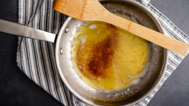 brown butter in frying pan atop kitchen towel with wooden spatula 