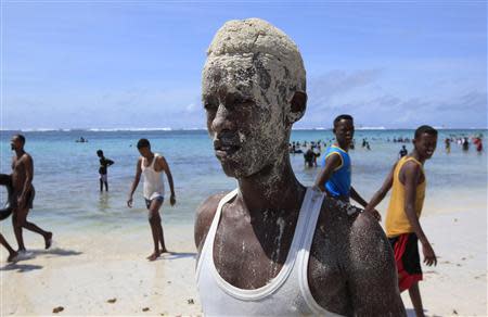 A man, who is covered in sand, poses for a photograph on Lido beach in Mogadishu October 4, 2013.REUTERS/Omar Faruk