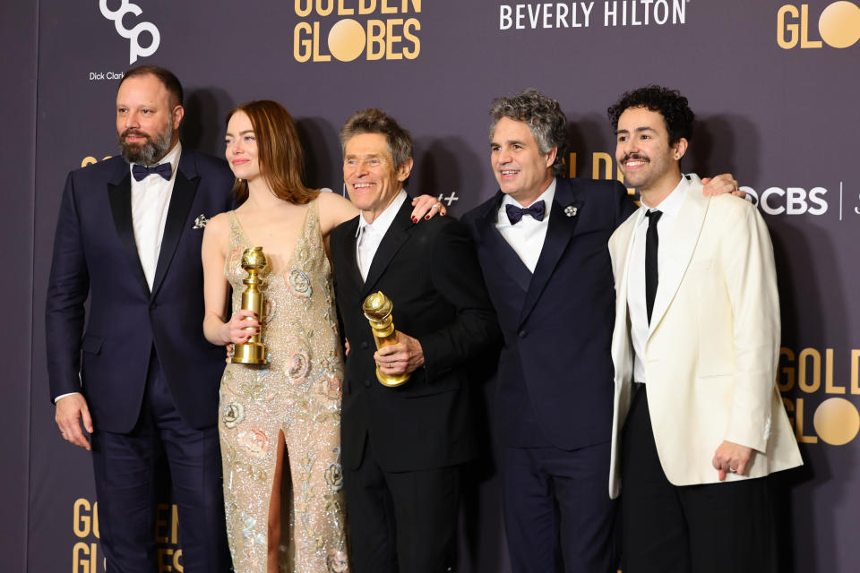 The cast and director of Poor Things pose for photos backstage with their awards