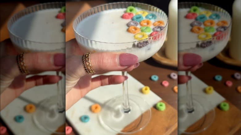 Hand holding a Froot Loops cocktail in a coupe glass