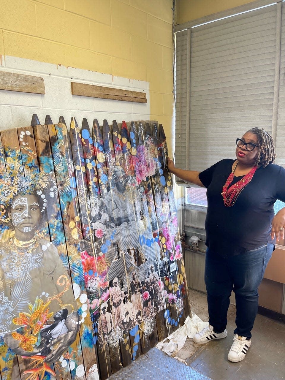 Artist Lavett Ballard is shown in her Willingboro studio with one of her wooden fence mixed-media collage pieces.