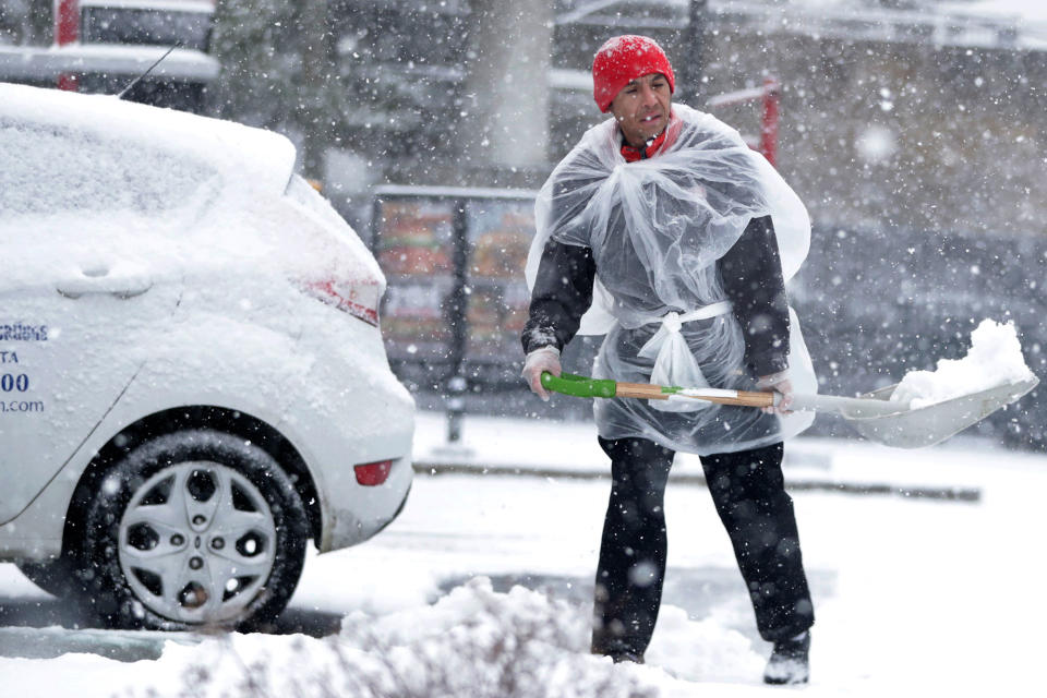 <p>A restaurant employee uses a large bag for protection while shoveling snow off the parking lot during a snowstorm, Wednesday, March 21, 2018, in Jersey City, N.J. (Photo: Julio Cortez/AP) </p>