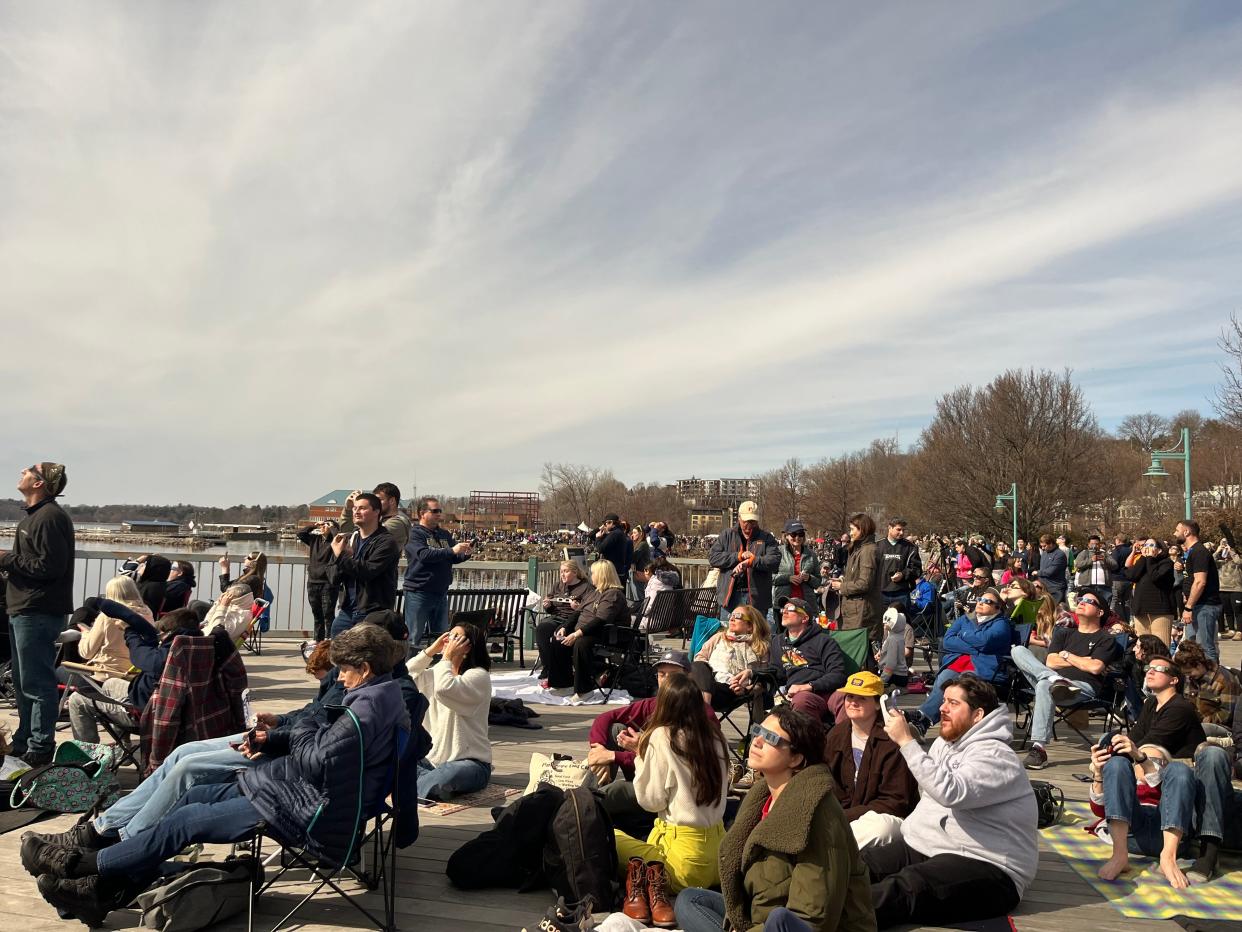 A huge crowd of eclipse watchers sits on the boardwalk in front of Lake Champlain in Burlington, VT.