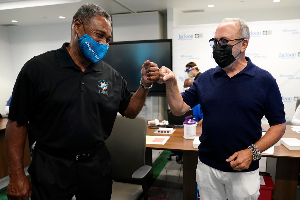 Former Miami Dolphins football player Nat Moore, 69, left, bumps fists with music producer Emilio Estefan, 67, right, before receiving the Pfizer-BioNTech COVID-19 vaccine at Jackson Memorial Hospital on Wednesday, Dec. 30, 2020, in Miami, Fla. Jackson Health System is starting to vaccinate people over the age of 65 this week.