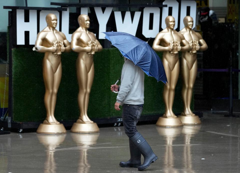 A pedestrian shields himself from strong winds and rain on Hollywood Boulevard during Tropical Storm Hilary, Sunday, Aug. 20, 2023, in Los Angeles. (AP Photo/Chris Pizzello)