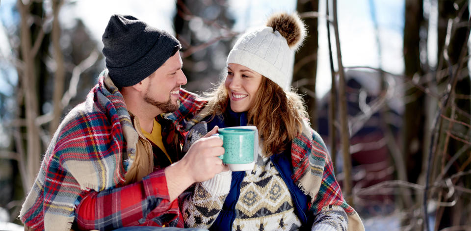 Couple in love enjoying a tender moment in fresh snow during wintertime and drinking hot chocolate together (julief514 / Getty Images stock)