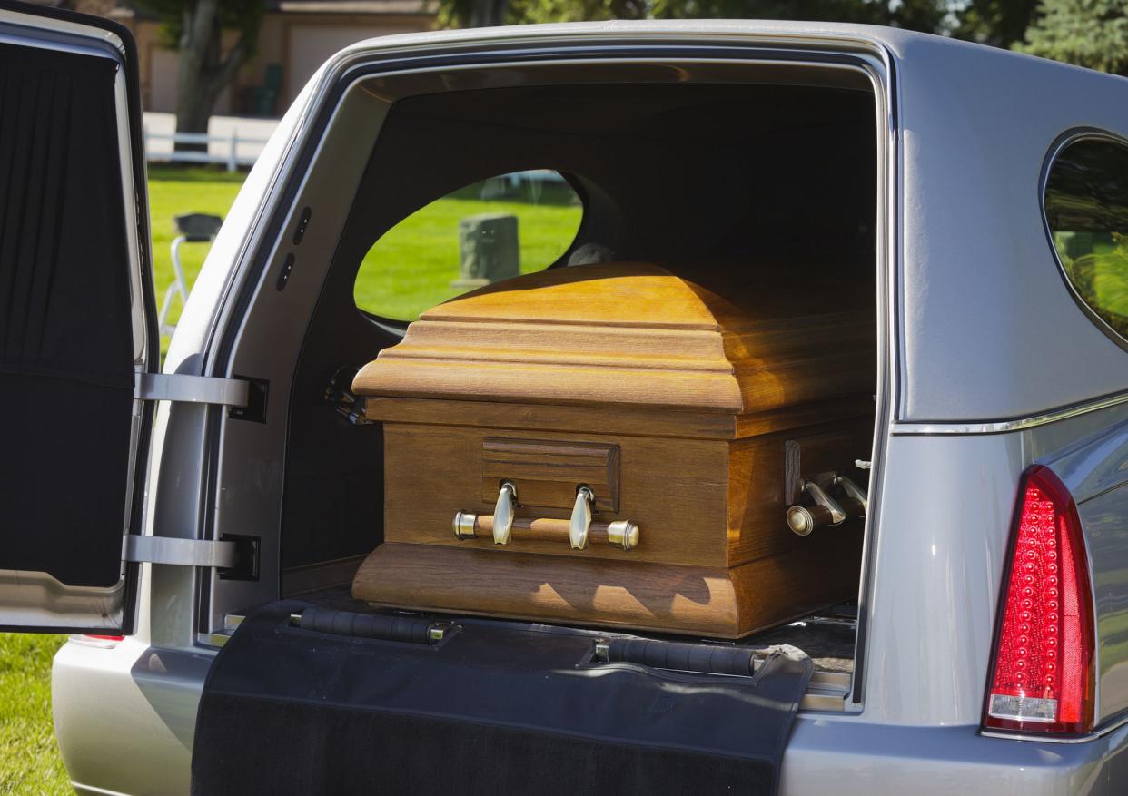 A casket in the back of an open hearse.