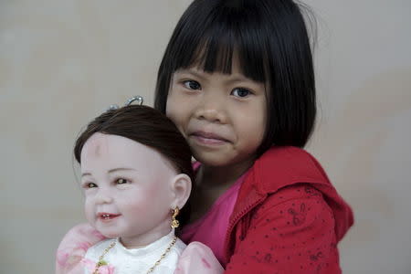 Prew, 6, smiles as she holds up her "child angel" doll inside a department store in Bangkok, Thailand, January 26, 2016. REUTERS/Athit Perawongmetha