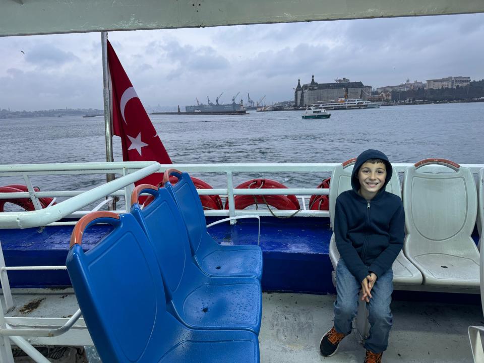 Boy sitting on rooftop deck of Istanbul ferry 