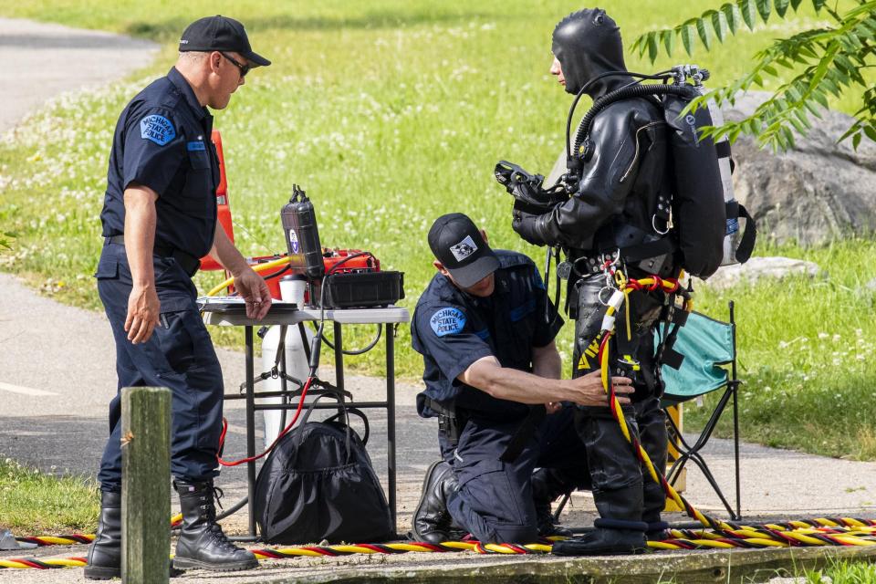 Police search the Kalamazoo River near Verburg Park, Tuesday, June 18, 2019, after finding the bodies of a mother and child inside a submerged vehicle, in Kalamazoo, Mich. Police believe a second child, who is missing, may also have been inside the vehicle when it entered the water late Monday evening. (Joel Bissell/Kalamazoo Gazette via AP)