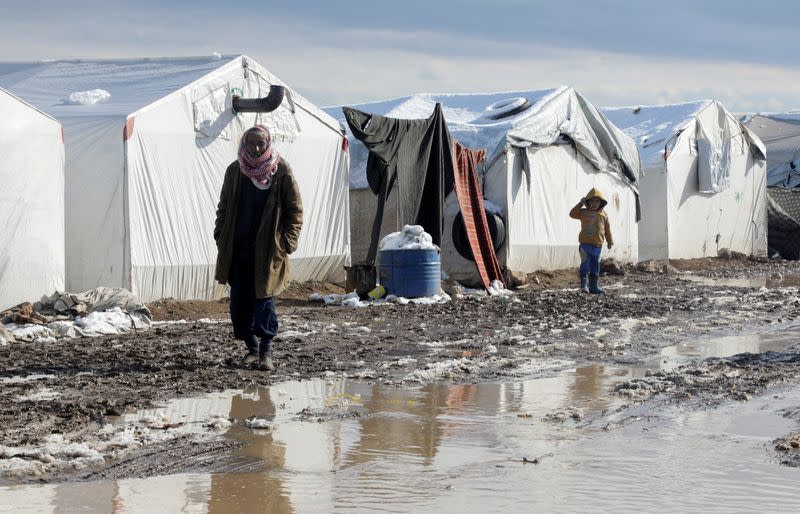 A man walks through mud near tents at a camp for internally displaced people in northern Aleppo countryside