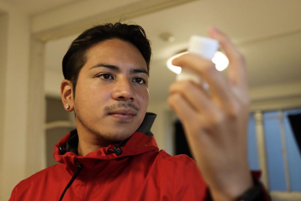 young latin man taking morning vitamins in the kitchen