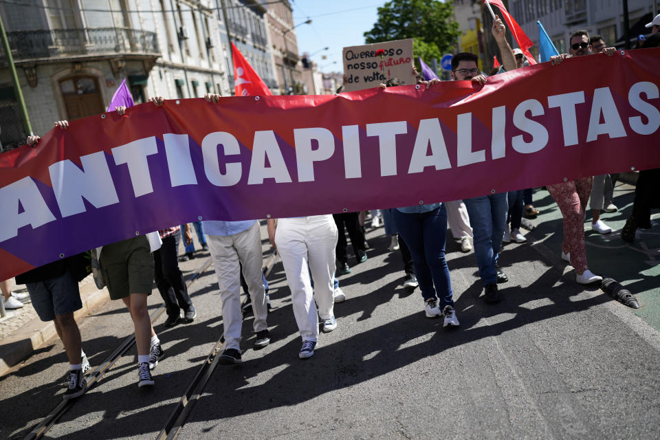 A group of protesters carry a banner with the word "Anti-capitalists" in Portuguese during a May Day rally in Lisbon, Monday, May 1, 2023. (AP Photo/Armando Franca)
