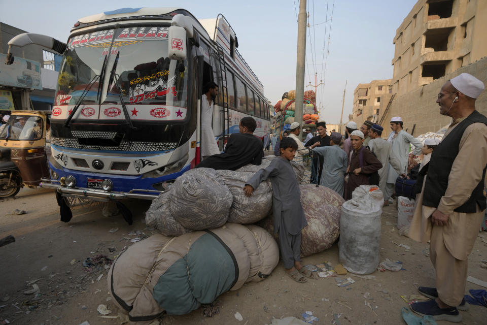 Familias afganas esperan para subir a autobuses que los lleven de regreso a su país, Karachi, Pakistán, el 30 de octubre de 2023. (AP Foto/Fareed Khan).