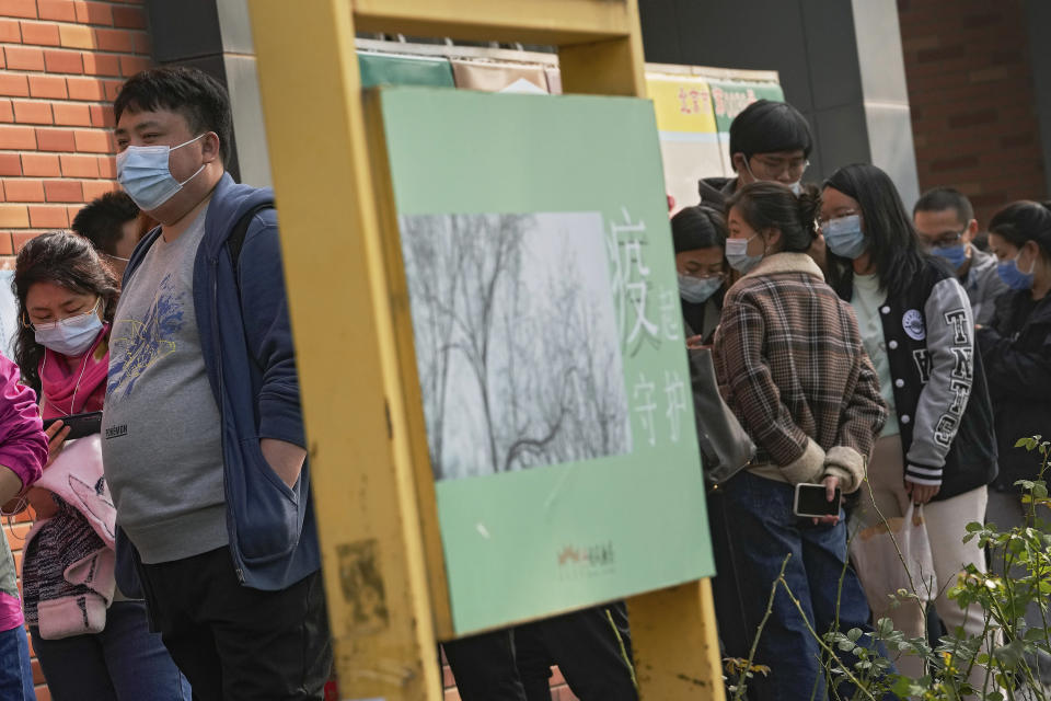 Residents wearing face masks to help curb the spread of the coronavirus line up to receive booster shots against COVID-19 at a vaccination site displaying a poster baring the words: "Epidemic protection" in Beijing, Monday, Oct. 25, 2021. A northwestern Chinese province heavily dependent on tourism closed all tourist sites Monday after finding new COVID-19 cases. (AP Photo/Andy Wong)