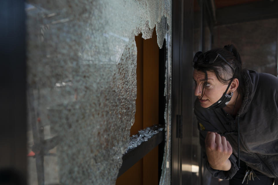 Megan Culverhouse, an employee at John Fluevog shoe store, cleans up broken glass from a window that was hit by gunfire from an early morning shooting Sunday, June 21, 2020, in Minneapolis' Uptown neighborhood. (Jerry Holt/Star Tribune via AP)