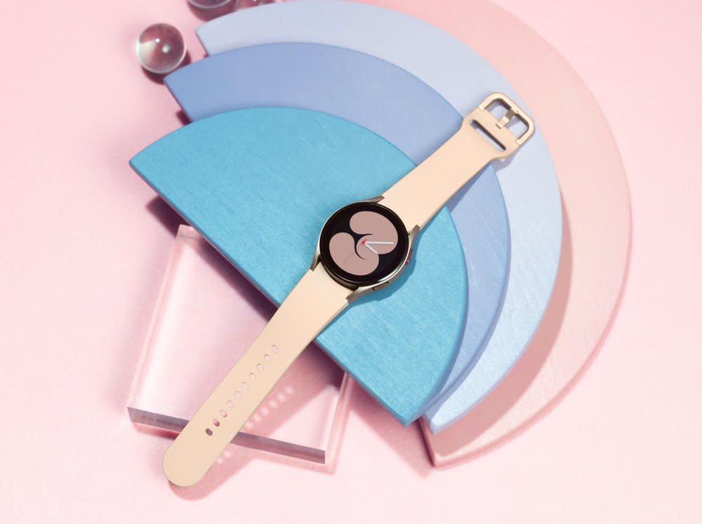 A Samsung Galaxy Watch 4 is photographed against a pink background. 