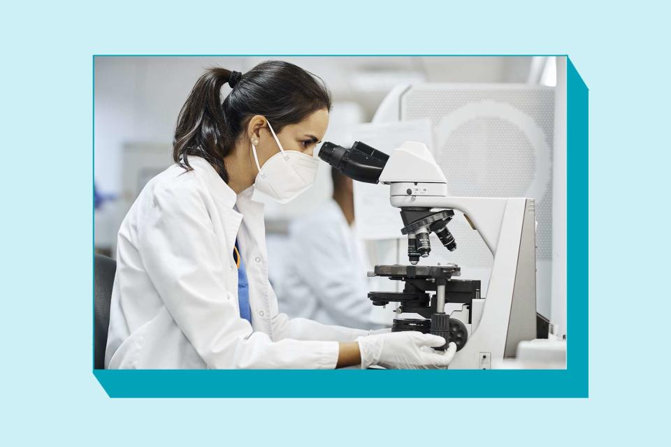 Female doctor doing research in laboratory. Side view of female doctor using microscope during research in laboratory.