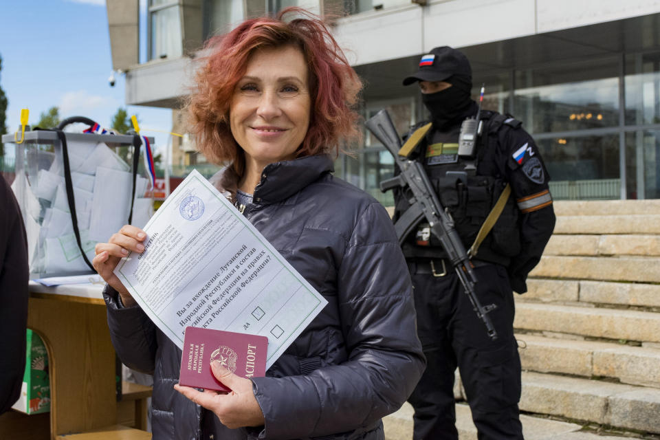 FILE - A woman shows her ballot to journalists prior to voting in a referendum in Luhansk, Luhansk People's Republic controlled by Russia-backed separatists, eastern Ukraine, Saturday, Sept. 24, 2022. Voting began Friday in four Moscow-held regions of Ukraine on referendums to become part of Russia. (AP Photo/File)