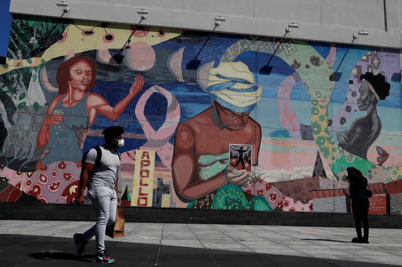 Un hombre con mascarilla pasa por un mural en el barrio de Harlem de la ciudad de Nueva York, Nueva York, EEUU, el 9 de julio de 2020