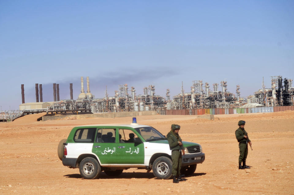 FILE - Algerian soldiers stand guard during a visit for news media, organized by the Algerian authorities, at the gas plant in Ain Amenas, seen in background, Friday, Jan. 31, 2013. While Africa's natural gas reserves are vast and North African countries like Algeria have pipelines already linked to Europe, a lack of infrastructure and security challenges have long stymied producers in other parts of the continent from scaling up exports.(AP Photo, File)