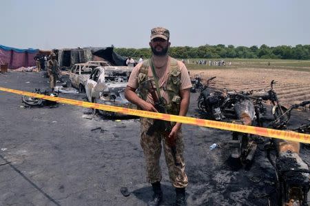 A soldier stands guard at the scene of an oil tanker explosion in Bahawalpur, Pakistan June 25, 2017. REUTERS/Stringer