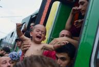 A migrant holds a crying boy out of a local train that was stopped in the Hungarian city of Bicske on September 3, 2015