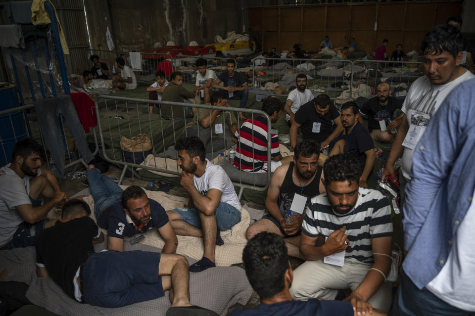 Survivors of a shipwreck sit inside a warehouse where are taking shelter at the port in Kalamata town, about 240 kilometers (150miles) southwest of Athens, on Thursday, June 15, 2023. A fishing boat crammed to the gunwales with migrants trying to reach Europe capsized and sank Wednesday June 14 off the coast of Greece, authorities said, leaving at least 79 dead and many more missing in one of the worst disasters of its kind this year. (Angelos Tzortzinis, Pool via AP)