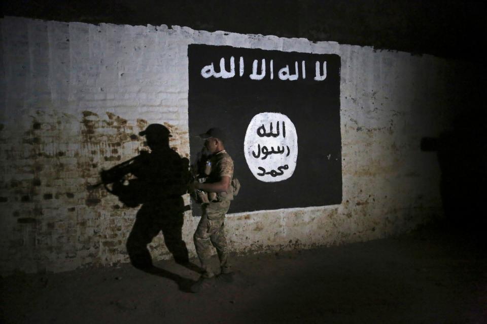An Iraqi soldier inspects a recently discovered train tunnel, adorned with an Islamic State group flag, that was turned into a training camp for ISIS fighters in Mosul, Iraq, in March 2017.