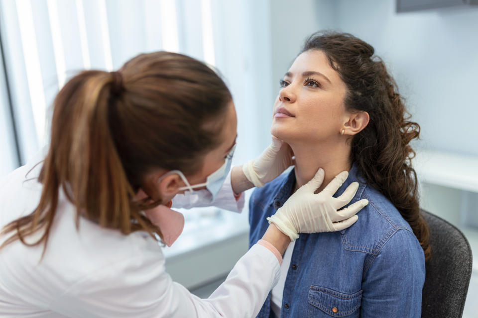 Lupus medicine, healthcare and medical exam concept - doctor or nurse checking patient's tonsils at hospital. Endocrinologist examining throat of young woman in clinic