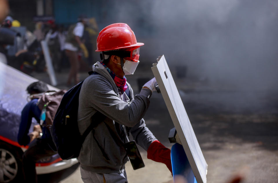 An anti-coup protester with a makeshift shield braves teargas during a demonstration in Yangon, Myanmar Thursday, March 4, 2021. Demonstrators in Myanmar protesting last month's military coup returned to the streets Thursday, undaunted by the killing of scores of people the previous day by security forces. (AP Photo)