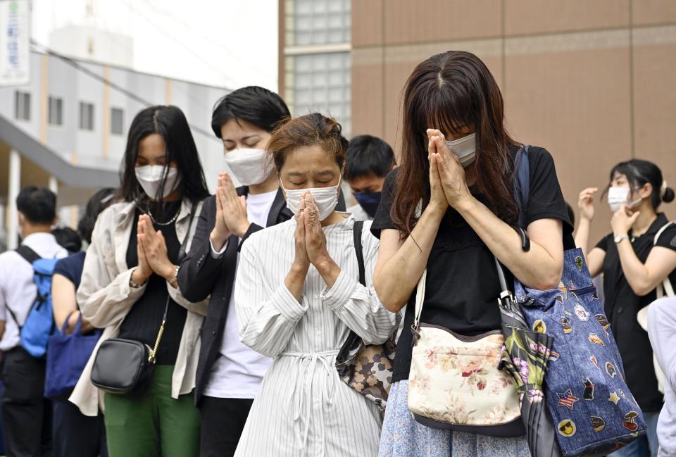 People offer prayer near the site where former Japanese Prime Minister Shinzo Abe was fatally shot in Nara, western Japan Friday, July 15, 2022. Many people mourned the death of Abe at the site where he was gunned down during a campaign speech a week ago Friday, shocking a nation known for its low crime rate and strict gun control. (Kyodo News via AP)