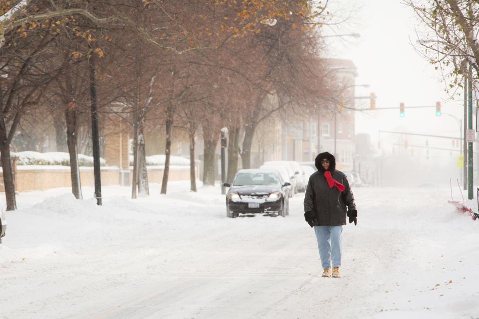 A woman walks down the middle of the street through the blowing snow in Buffalo, New York, November 19, 2014. An autumn blizzard dumped a year's worth of snow in three days on Western New York state, where five people died and residents, some stranded overnight in cars, braced for another pummeling expected later on Wednesday. REUTERS/Lindsay DeDario (UNITED STATES - Tags: ENVIRONMENT DISASTER)