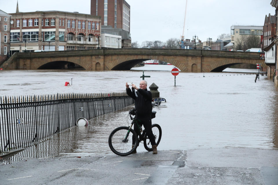 A man on a bicycle takes photos in front of floodwaters in central York.